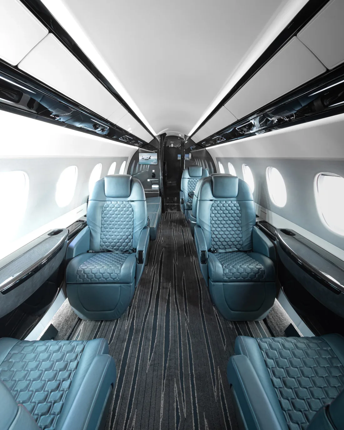 Blue-grey quilted seats beside the central aisle of a business-jet cabin.